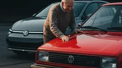 Man poetst rode Volkswagen, zwarte Volkswagen op achtergrond, buiten, daglicht.